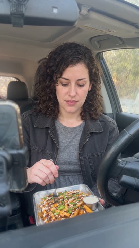 Creator eating loaded fries in the front seat of a car